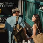 Romantic Date Destinations - Back view of young happy diverse couple with bags looking at each other near underground