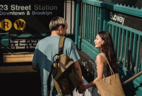 Romantic Date Destinations - Back view of young happy diverse couple with bags looking at each other near underground