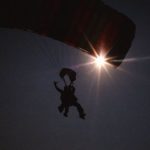 Skydiving And Paragliding - Low Angle Shot of Paragliding People Sulhouette, and Sun on Dark Sky