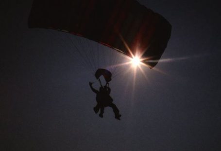 Skydiving And Paragliding - Low Angle Shot of Paragliding People Sulhouette, and Sun on Dark Sky